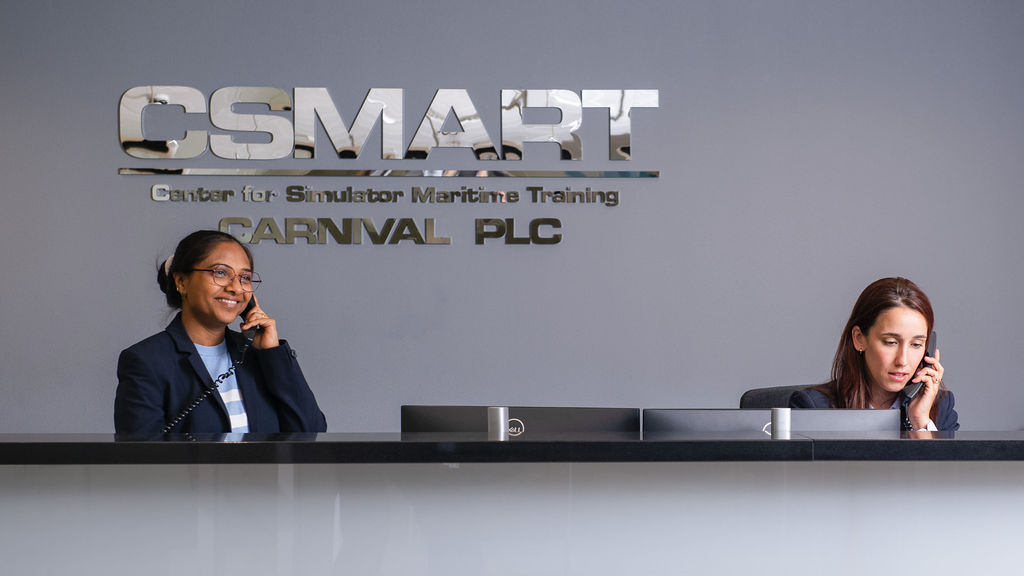Two receptionists answering phones beneath the CSMART reception sign