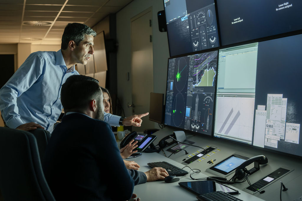 Instructor points at engine simulator screens beside trainees
